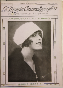 The cover of La Rivista Cinematografica, featuring a women wearing a white cloche hat. Her hair is short and dark and her eyes are heavily made up. She is in three-quarter profile.